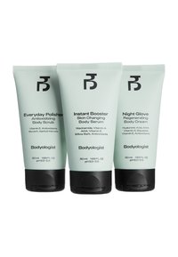 Drei Tuben von Hautpflegeprodukten: mintgrün mit schwarzen Akzenten, die ein Logo zeigen. Die Etiketten zeigen Produktnamen und Inhaltsstoffe.