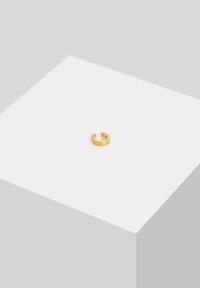 Goldfarbener Ring mit glatter Oberfläche und offenem Design, das ein dezentes Akzentdetail für zusätzliche Eleganz aufweist. Schlichte geometrische Form.