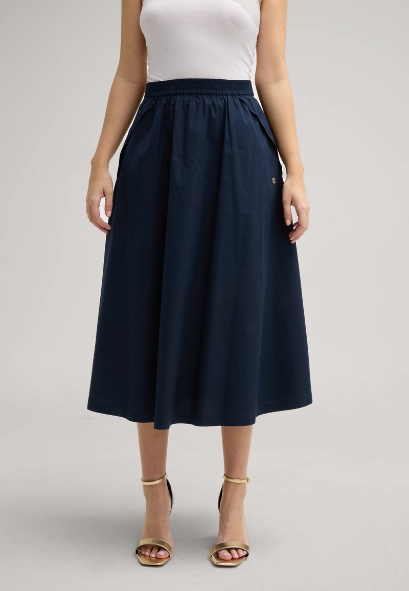 Marineblaue Midirock mit strukturierter Oberfläche, elastischem Bündchen, seitlichen Taschen und einem kleinen Logodetail an der Taille.