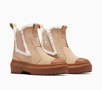 Botas de tobillo de ante beige con forro de piel de oveja, que cuentan con tapas de goma en los dedos, suelas exteriores gruesas marrones y paneles laterales elásticos. Logo icónico presente.
