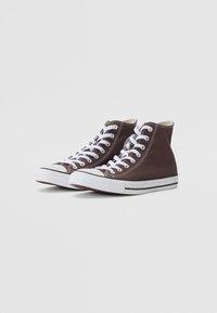 Zapatillas de lona altas en marrón oscuro con cordones blancos, punta de goma y suela de rayas en blanco y negro. Textura suave y diseño clásico.