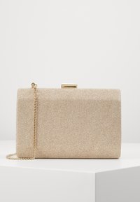 Obdélníková psaníčko v barvě zlata s texturovanou látkou, s řetízkovým popruhem a zapínáním na sponu. Barva: světle béžová s jemným leskem.