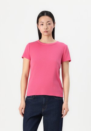 Rosa ribbet t-skjorte med kort erm, rund hals og en tettsittende silhuett, laget av mykt stoff og kombinert med mørkeblå jeans.
