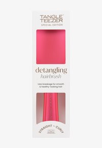 Szczotka do rozczesywania Tangle Teezer w jasnoróżowym kolorze, z eleganckim ergonomicznym kształtem i teksturowanym uchwytem, zapakowana w białe pudełko z złotym napisem.