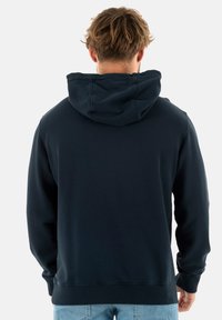 Sudadera azul marino con una textura suave, con capucha ajustable y puños y dobladillo acanalados. Diseño simple y funcional.