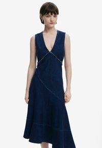 Jeansklänning i mörkblått med V-hals och asymmetrisk nederkant, med kontrasterande sömmar och en figursydd midja.