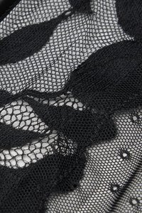 Czarna koronka z misterną siateczką w kwiatowy wzór i falowanymi brzegami, uzupełniona o okrągłe wycięcia na całej powierzchni.