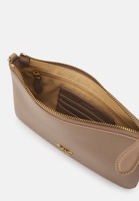 Beige leren clutch met gouden rits. Van binnen heeft deze een gladde tanvoering, een klein ritsvak en sleuven voor kaarten.