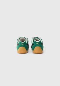 Pair of green suede Puma sneakers with gum soles, viewed from the back against a plain white background.