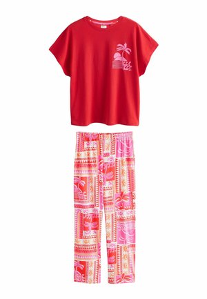 Rode top met korte mouwen met een print van een roze palmboom en zonsondergang, gecombineerd met roze en rode broek met elastische taille en patroon.