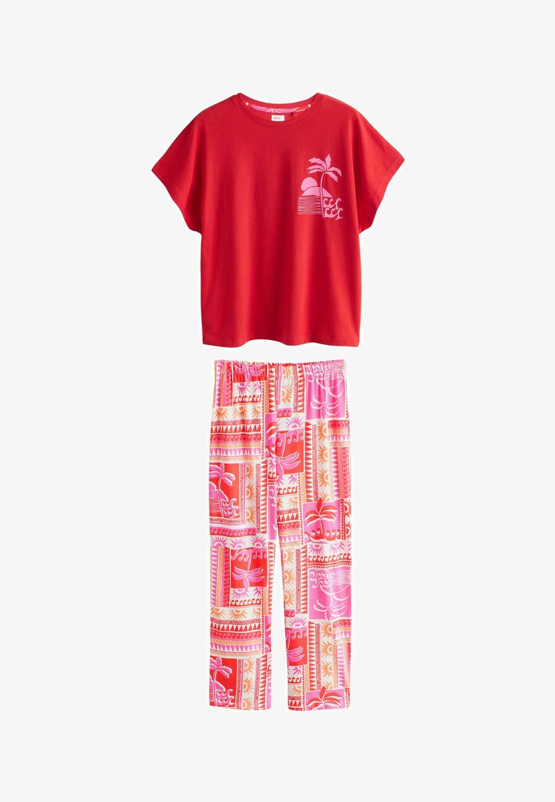 Sarkans īsroku tops ar rozā palmas koku un saulrieta apdruku, kombinēts ar rozā un sarkanas rakstu elastīga vidukļa biksēm.