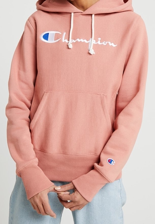Vaaleanpunainen hupullinen collegepaita pehmeästä kankaasta, jossa on etutasku. Rinnassa ja hihassa valkoinen "Champion"-logo ja sininen yksityiskohta.