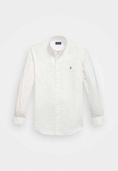 Hvit langermet skjorte med knapper laget av bomull, med et lite, brodert logo på brystet og en klassisk kragedesign.