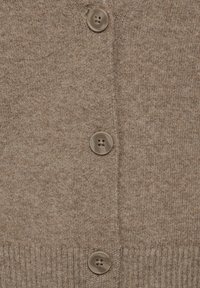 Beige gestrickte Strickjacke mit fünf braunen Knöpfen, geripptem Saum und einer weichen Textur mit einem dezenten Muster.