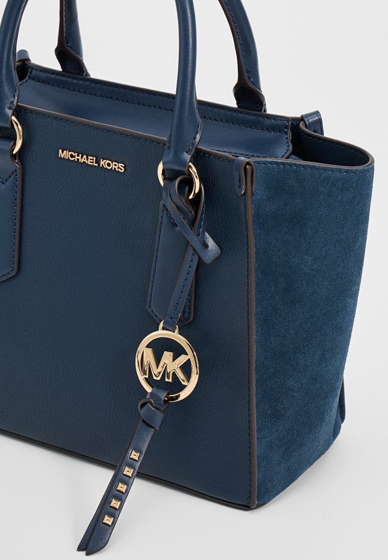 Borsa Michael Kors blu navy con texture in pelle e microfibra, charm con logo dorato, doppio manici e dettagli decorativi con borchie sulla tracolla.