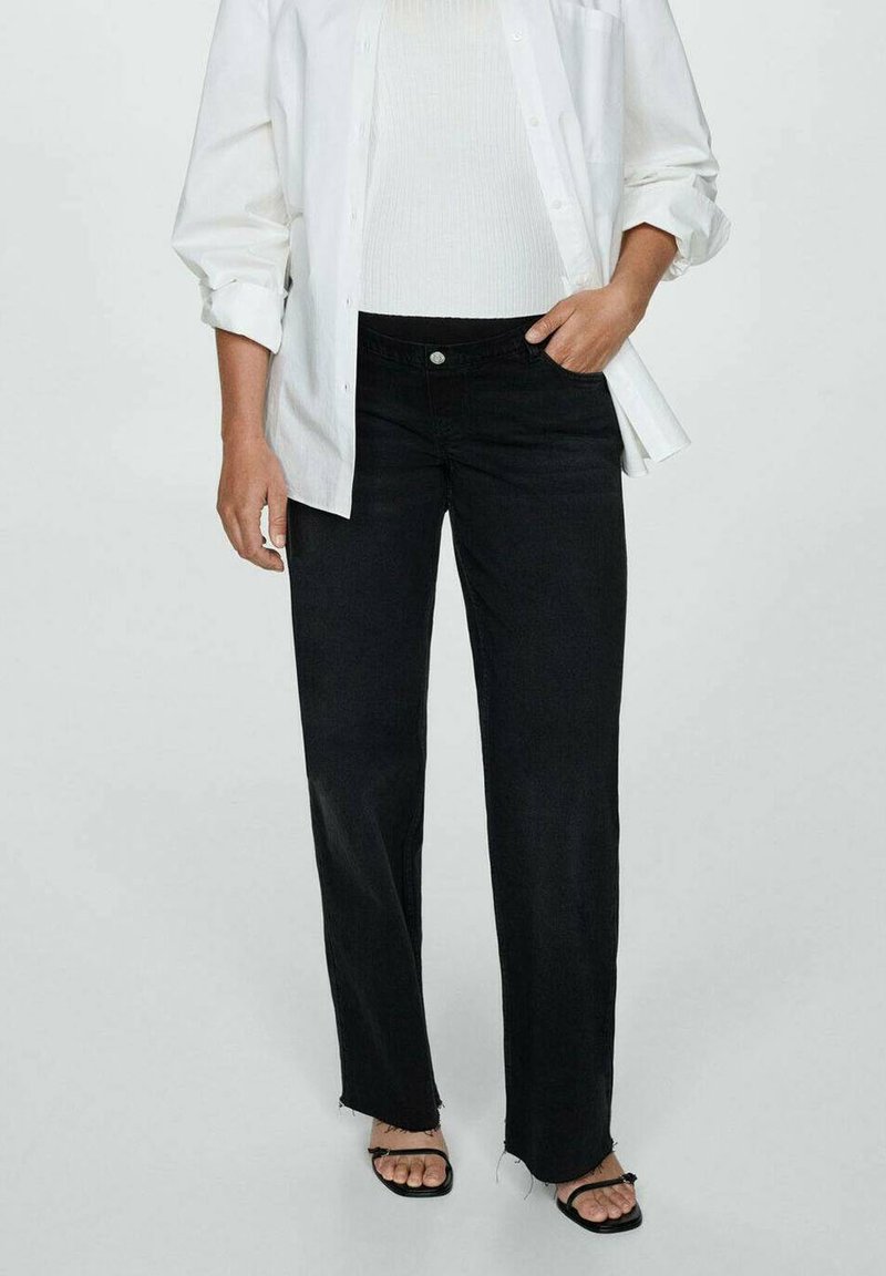 Black high-waisted jeans with a straight leg fit, frayed hem, and front pockets, paired with a white top and oversized white shirt.