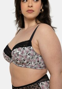 Soutien-gorge noir et blanc avec un motif de feuilles fleuries en rose et gris, doté de dentelle et de fines bretelles réglables. Conçu avec une texture douce.