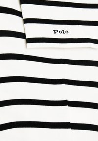 Czarna i biała koszulka polo w paski, z krótkimi rękawami i złożonym kołnierzykiem. Nazwa marki "Polo" jest wyhaftowana na kołnierzyku.