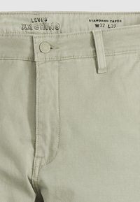 Pantalon chino Levi's XX beige clair avec fermeture par boutons et passants de ceinture, taille W32 L32, coupe standard effilée.