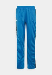 Blå träningbyxor gjorda av ett mjukt tyg. Har ett elastiskt midjeband och svarta sidostrickor med vita detaljer.