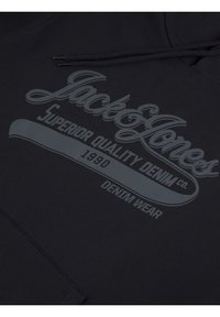 Zwarte hoodie met een groot, grijs grafisch textelement met de teksten "Jack & Jones," "Superior Quality Denim Co.," en "1990 Denim Wear" in reliëfdesign.