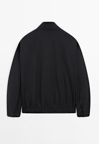 Black long-sleeve jacket with a stand collar and elasticized waistband, shown from the back on a white background.