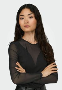 Long-sleeve black top with a sheer neckline, featuring a deep V design. Smooth fabric with a slight sheen and fitted sleeves.