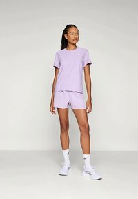 Heled lilla sportlik komplekt, mis koosneb lühikese varrukaga särgist ja lühikestest püksidest. valmistatud sileda kangaga, millel on mugav lõige. Rindkere peal on Adidas logo.