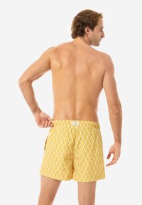 Shorts de baie galbeni, cu un model în diamond, talie elastică și buzunare laterale, realizate dintr-un material ușor. Vizualizare din spate.