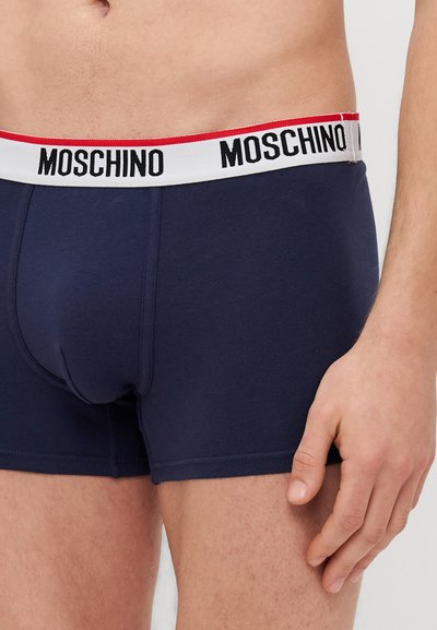 Marineblaue Boxershorts aus weichem Stoff, mit einem weißen Bund, auf dem "MOSCHINO" in Schwarz und roten Akzenten steht. Taillierte Passform mit konturiertem Pouch.
