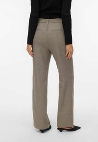 Heledast pruunist tekstuuriga laiade säärtega püksid elastse vöökohaga, millel on kaks tagataskut. Komplektis mustad teravate ninadega kingad.