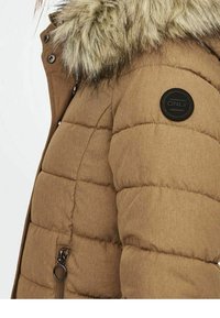 Pohodlná hnědá bunda s umělou kožešinou na límci, se zástěrou s černým kulatým odznakem, zipem a vodorovným švem.