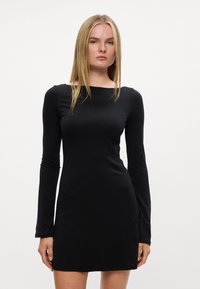 Vestido preto de manga longa feito de tecido suave, com decote reto e silhueta ajustada, terminando acima do joelho.