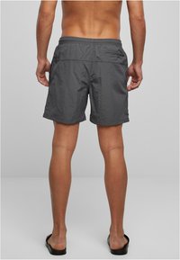 Halli ujumispüksid kerge materjaliga, millel on elastne vöökoht ja tagaküljel tõmblukuga tasku, lõdva lõikega ja üle põlve pikkusega.