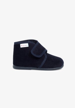Chausson enfant en velours côtelé bleu marine avec bride velcro réglable et semelle souple, étiqueté d'une étiquette colorée "Pramones".