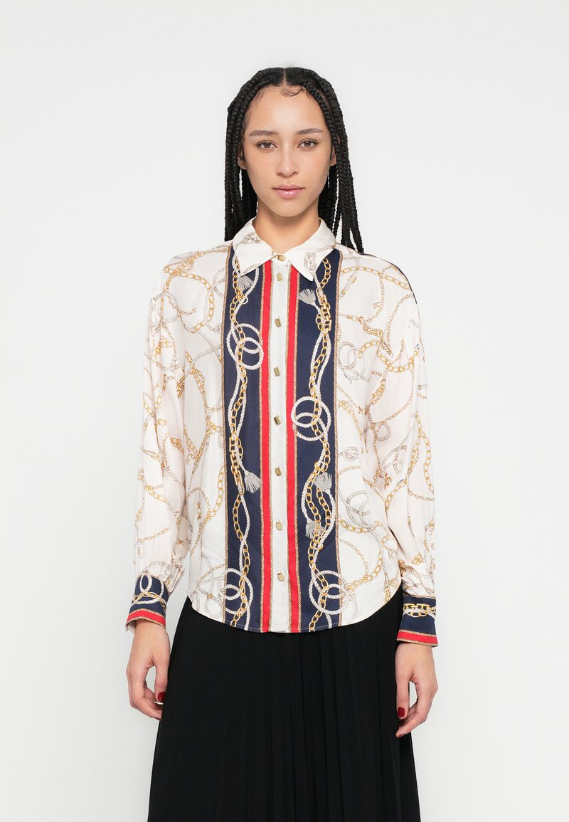Košulja dugih rukava na kopčanje u krem boji s uzorkom zlatnog lanca, sadrži tamnoplave i crvene okomite pruge te kontrastne manžete.