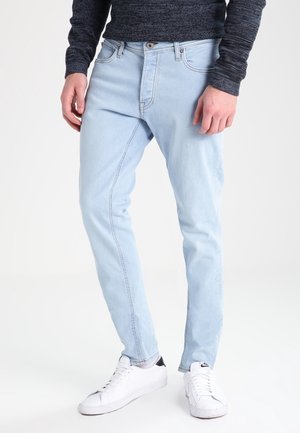 Ljusblå denimjeans med slim fit, med en traditionell femfickdesign och subtila blekningar. Kombinerat med vita sneakers.