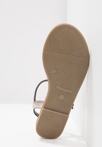 Semelle de sandale avec motif géométrique texturé et bride, affichant le nom de la marque "Tamaris" et la taille 37.