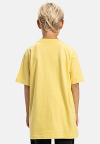 Camiseta de algodón amarilla con mangas cortas, cuello redondo y un corte relajado. Textura suave con un diseño liso y sin patrones ni adornos.