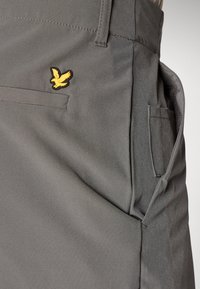 Gray shorts made of lightweight fabric, featuring a small yellow bird logo, side pocket, and clean, simple stitching.