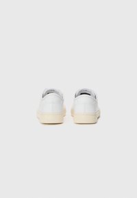 Vita lädersneakers med låg design, beige gummisålar och en mjuk yta. Rund tå och minimalistisk detaljering på bakpanelen.