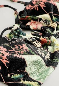 Zwart bikini-top met bloemenprint van textuurstof, met accenten in roze, groen en crème. De hardware omvat een gouden sluiting.