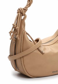 Beežist nahast käekott sõlmitud õlarihmaga, lukuga tasku, sileda tekstuuri ja ümara kujuga. Omaduste hulka kuuluvad minimalistlikud disainielemendid.