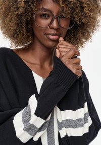 Zwart-wit gestreepte trui met een V-hals en geribbelde manchetten, gemaakt van een gestructureerde gebreide stof, met een losse pasvorm en een gelaagd ontwerp.