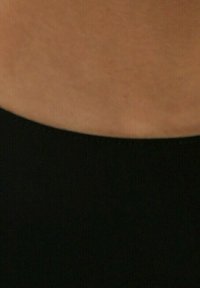 Cinturilla de tela negra con una textura suave, unida a un tono de piel más claro, centrándose en la transición entre materiales.