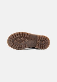 Semelle extérieure en caoutchouc marron avec des motifs de bande de roulement texturés pour une bonne adhérence. Présente des sections surélevées et des accents hexagonaux. Durable et conçue pour une traction optimale.