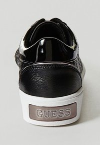 Czarne sneakersy z teksturowaną skórzaną cholewą i błyszczącymi akcentami z lakierowanej skóry. Wyposażone w białą gumową podeszwę z metalicznym logo "GUESS" na pięcie.