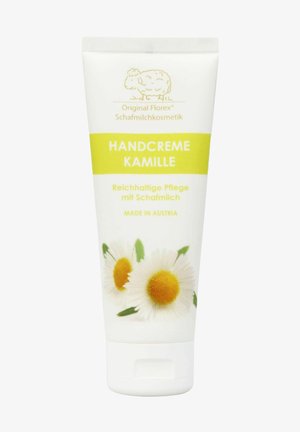 Handcreme in einer weißen Tube mit gelben Akzenten, die Kamillenblüten zeigt. Der Text beinhaltet "Handcreme Kamille", "Reichhaltige Pflege mit Schafmilch".