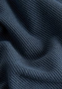 Tessuto blu navy texturizzato con un fine motivo a righe, che mostra un drappeggio morbido e flessibile e una leggera lucentezza. Gli accenti offrono profondità visiva e dimensione.
