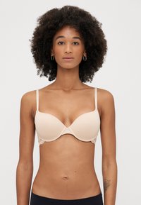 Sostenitore beige con coppe imbottite, dettagli in pizzo sui lati e spalline regolabili; design senza cuciture per una vestibilità liscia.